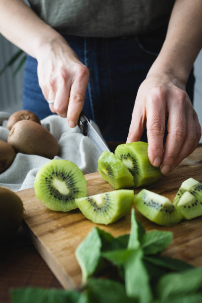istock Woman in the kitchen slicing kiwis. 1388825306