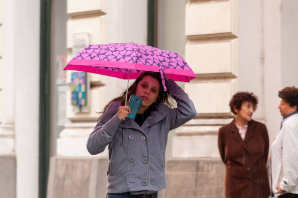 Timisoara, Romania - May 03, 2016: Woman walking on the street in the rain with an umbrella in hand. Real people.