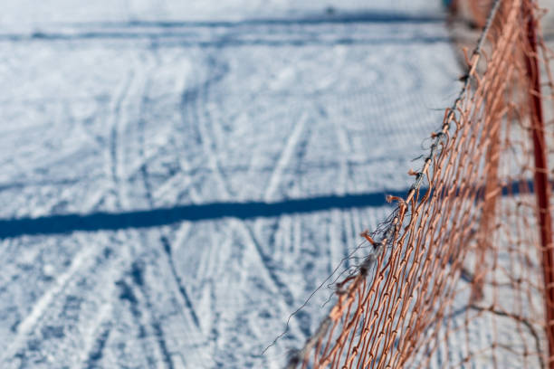 istock Orange security fence on a white snow sky track path 1388828760