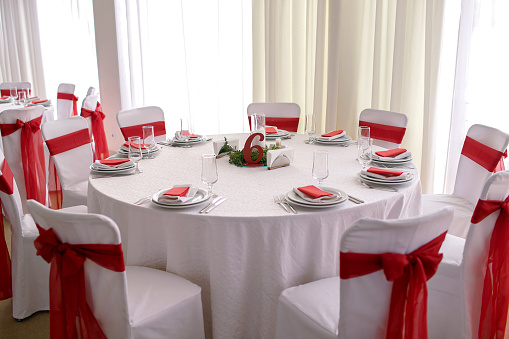 A beautiful table in the restaurant decorated with red ribbons, table number six is waiting for guests for a banquet