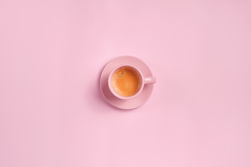 Cup of espresso coffee in a pink cup on pink background