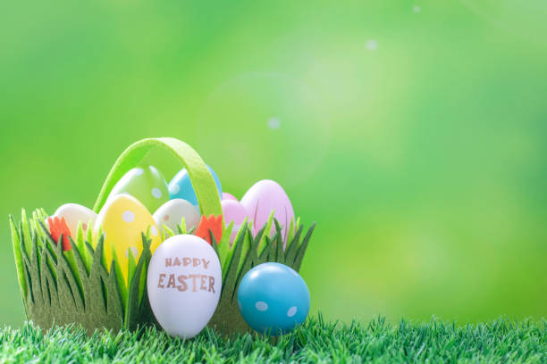istock Colorful decorated Easter eggs in a colorful felt basket with flowers on a green grass. 1388840751