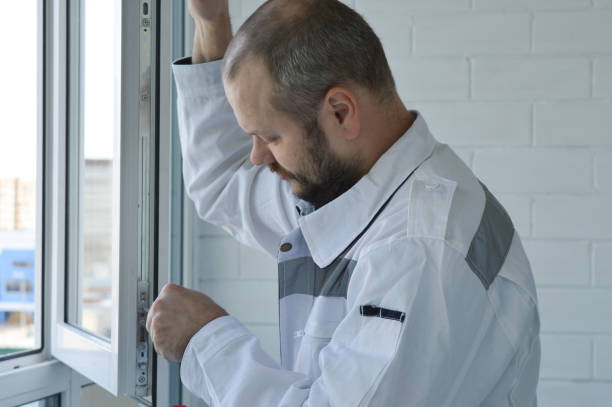 istock Construction worker dressed in a white jumpsuit repairing plastic window with screwdriver indoors, closeup 1388844468