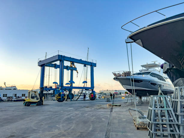 Yangyang County, South Korea - November 3rd, 2024: A large blue boat lift at Susan Port, positioned over the dock with a small vessel beneath, set against a vibrant sky and colorful breakwater murals.