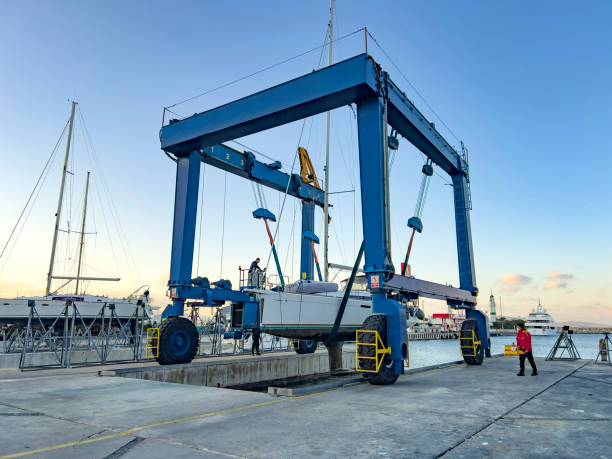 voilier soulevé par grue en cale sèche - crane shipyard construction pulley photos et images de collection