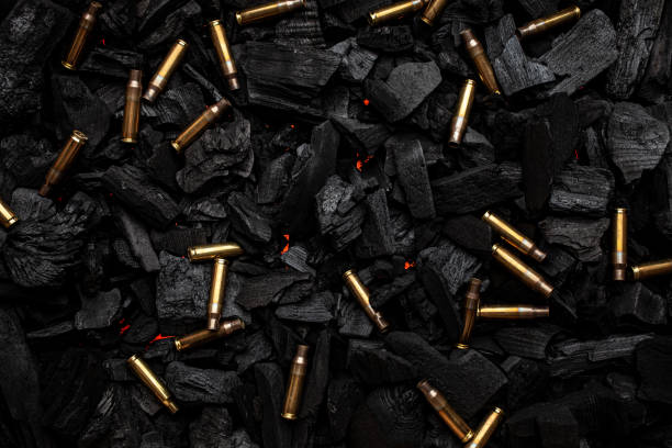 istock Empty shells from weapons on black smoldering coals. Consequences of the war. Dark background. 1388849660