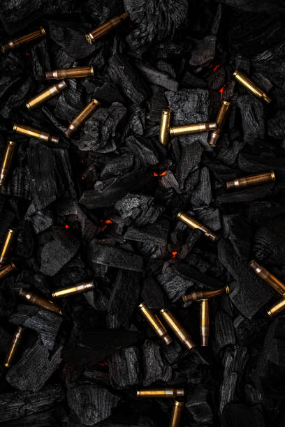 istock Empty shells from weapons on black smoldering coals. Consequences of the war. Dark background. 1388849662
