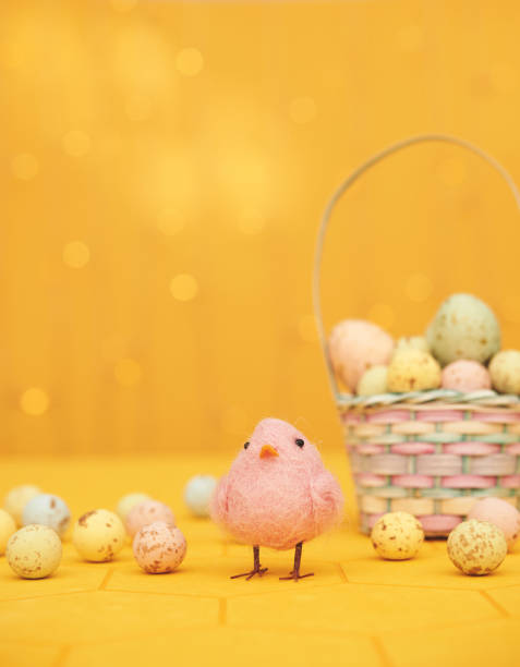 Yellow Easter background with Easter basket and Easter eggs and cute pink felt bird