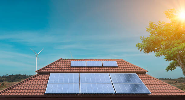solar panel on a roof of a house with wind turbines around. photovoltaic, alternative electricity source - solar panels house imagens e fotografias de stock