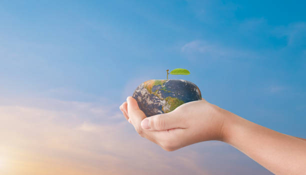 istock Child hands holding apple globe earth over blurred sunset sky background. World environment day concept 1388862623
