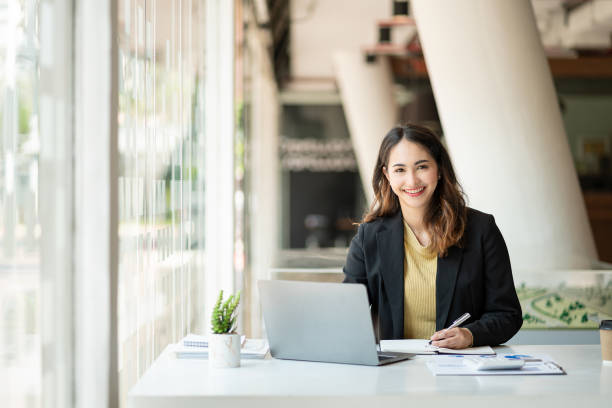 istock Young Asian businesswoman doing bookkeeping Finance Graph uses laptop while doing homework video calling abroad using friend internet connection business women use computers to analyze financial data 1388863435