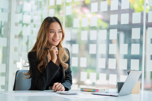 istock Young Asian businesswoman doing bookkeeping Finance Graph uses laptop while doing homework video calling abroad using friend internet connection business women use computers to analyze financial data 1388863468