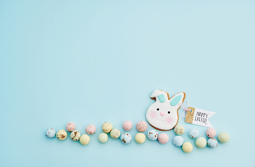 Pastel Easter background with Easter bunny cookie decoration and pastel chocolate Easter candy