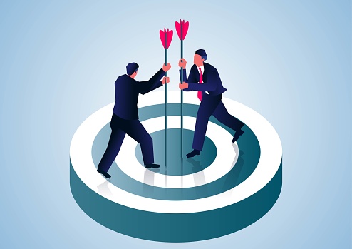 Two businessmen insert the arrow into the bullseye to complete the goal and compete together.