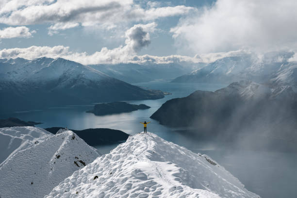 Man with open arms at Roy's Peak iconic lookout in winter season. Wanaka, New Zealand stock photo