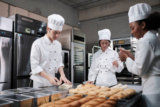 istock Chefs team in uniforms prepare to bake bread and pastry in stainless kitchen. 1388875503