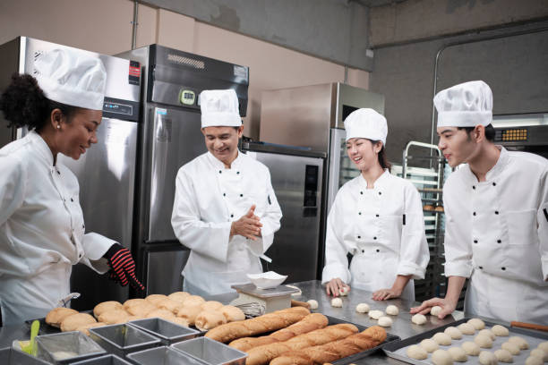 istock Chefs team in uniforms prepare to bake bread and pastry in stainless kitchen. 1388875520