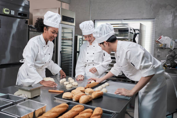 istock Chefs team in uniforms prepare to bake bread and pastry in stainless kitchen. 1388875524