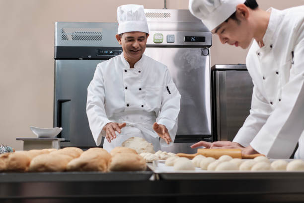 istock Asian male chefs in uniforms are preparing to bake bread in a stainless kitchen. 1388875540