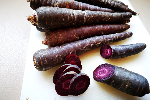 A focus scene of a bunch of purple carrots on chopping board.