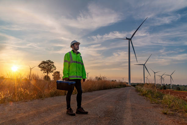 istock Engineer wearing uniform ,helmet hold document inspection work in wind turbine farms rotation to generate electricity energy. Green ecological power energy generation wind sustainable energy concept. 1388878920