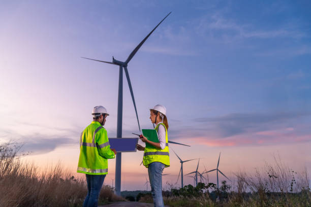 istock Engineer wearing uniform ,helmet hold document inspection work in wind turbine farms rotation to generate electricity energy. Green ecological power energy generation wind sustainable energy concept. 1388878921