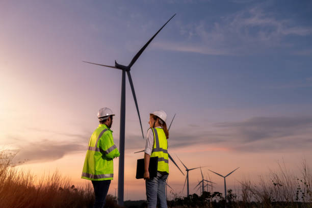 istock Engineer wearing uniform ,helmet hold document inspection work in wind turbine farms rotation to generate electricity energy. Green ecological power energy generation wind sustainable energy concept. 1388879002