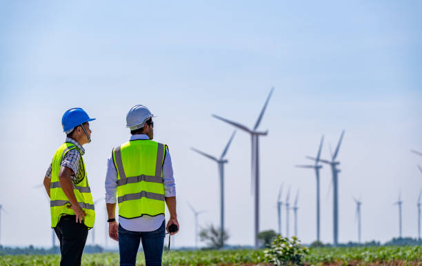 istock Engineer wearing uniform ,helmet hold document inspection work in wind turbine farms rotation to generate electricity energy. Green ecological power energy generation wind sustainable energy concept. 1388879103