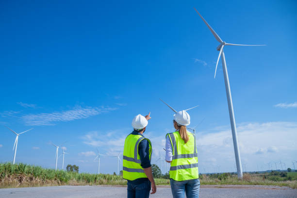 istock Engineer wearing uniform ,helmet hold document inspection work in wind turbine farms rotation to generate electricity energy. Green ecological power energy generation wind sustainable energy concept. 1388879152