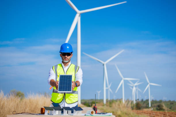 istock Engineer wearing uniform ,helmet hold document inspection work in wind turbine farms rotation to generate electricity energy. Green ecological power energy generation wind sustainable energy concept. 1388879685