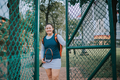 Asian Chinese mid adult female tennis player walking entering tennis court