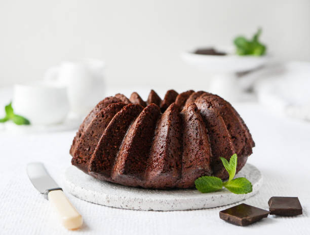 pastel de remolacha de chocolate sobre plato de madera blanca decorado con hoja de menta. comida de primer plano. - chocolate bundt cake fotografías e imágenes de stock