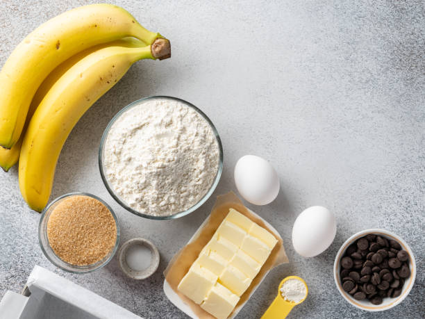 istock Banana bread (cake, pancakes or muffins) ingredients top view. Flour bowl, white eggs, butter, brown sugar, chocolate chips, bananas. Copy space. 1388891742