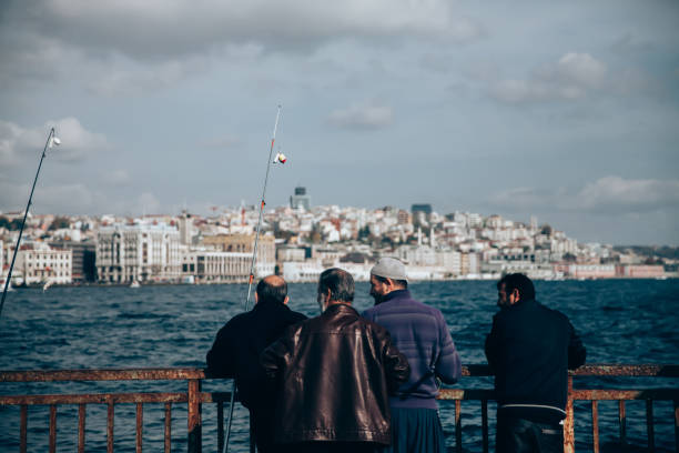 Istanbul, Turkey- January 6th, 2022: Turkish senior men fishing at galata bridge, which is the most popular activities among turkish men daily, also very interesting scene for tourist to watch.