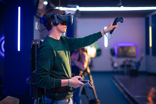 Young man and woman playing VR multiplayer video game. Entertainment club