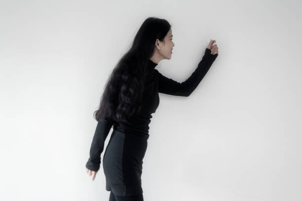 A businesswoman in black standing on a white wall