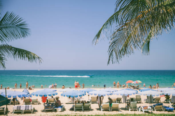 Phuket, Thailand - January 26, 2022: Tourists and locals enjoying sunshine at Karon Beach in Phuket. Phuket is well known as a popular travel destination because of its numerous idyllic pristine, tropical beaches.