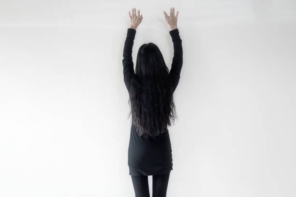A businesswoman in black standing on a white wall