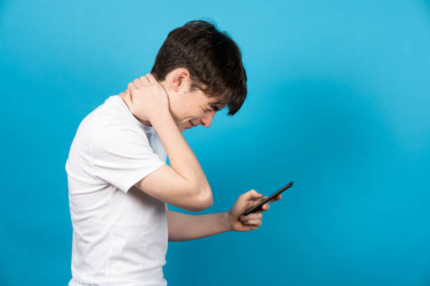 istock Teenager with neck pain using phone 1388896283