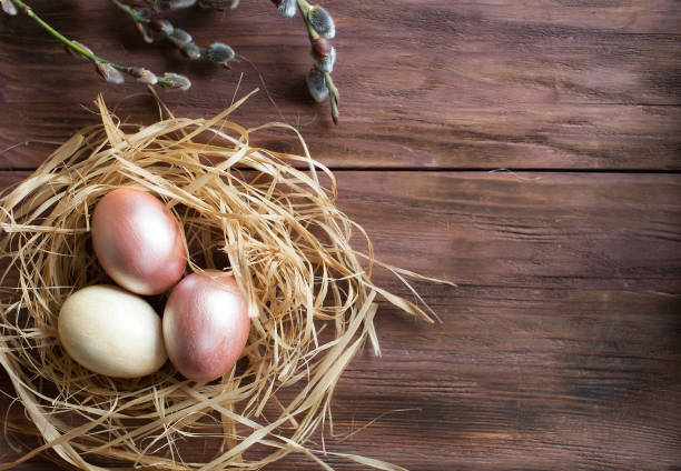 istock Pink and yellow Easter eggs in nest on wooden background.  Minimal easter concept. Easter card with copy space for text. 1388901930