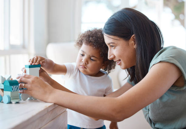 photo d’une jeune mère et de sa fille jouant avec un jouet à la maison - mother baby child playing photos et images de collection