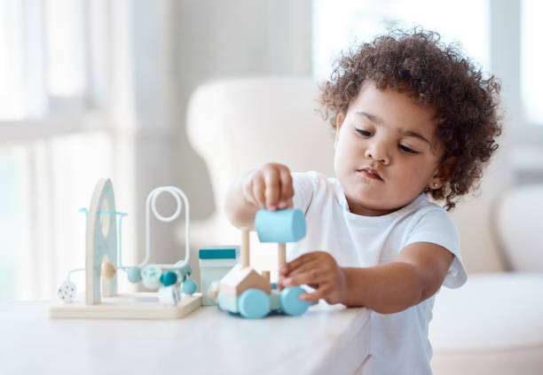 foto de una niña jugando con un juguete en casa - playing playful baby contemporary fotografías e imágenes de stock