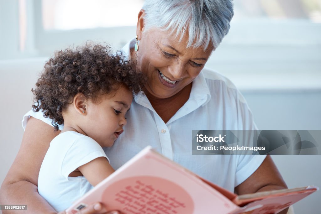 Shot of a mature grandmother reading her granddaughter a story at home A story before bedtime Grandmother Stock Photo