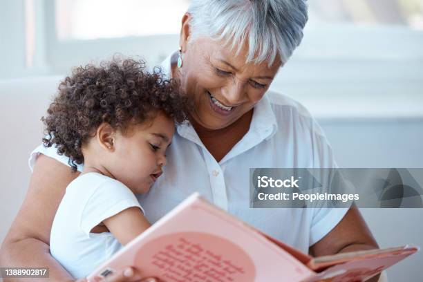 Shot Of A Mature Grandmother Reading Her Granddaughter A Story At Home Stock Photo - Download Image Now