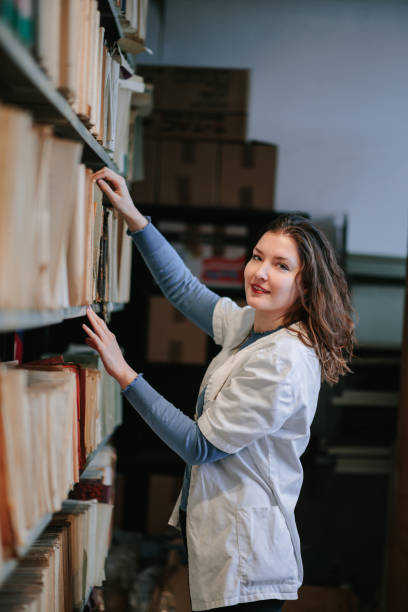istock University post-grad student in lab coat taking material from shelves in the library 1388905237