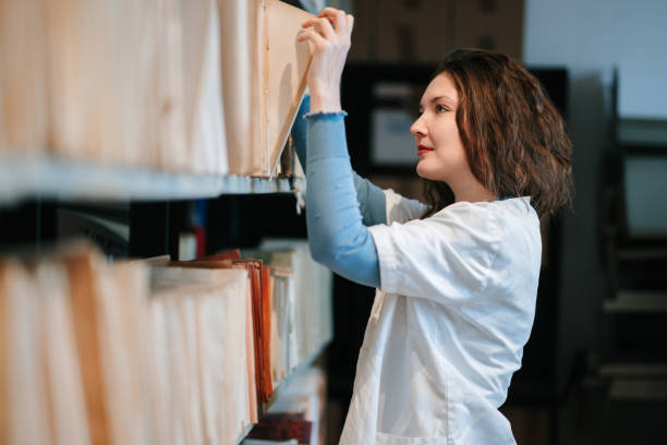 istock University student in lab coat choosing files from shelf in the library 1388905247