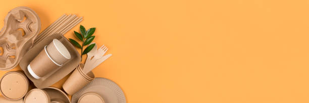 istock Banner with eco-friendly tableware set. Kraft paper utensils, paper containers and cups, bamboo cutlery on orange background, copy space. Street food paper packaging concept. Ethical consumerism, flat lay, mockup 1388905673