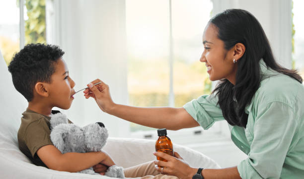自宅で咳止めシロップを飲む病気の小さな男の子のショット - cough remedy ストックフォトと画像