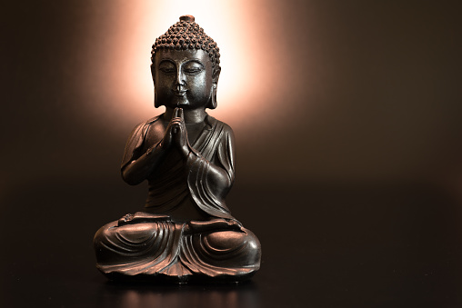 Buddha in atmospheric dark lighting with side light and selective focus