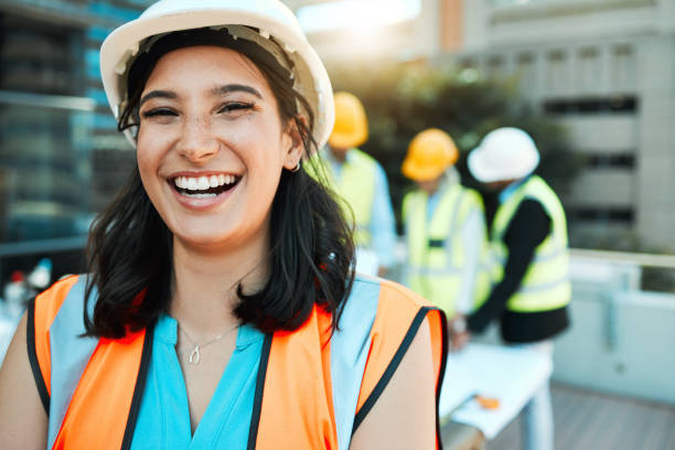 istock Shot of an attractive young contractor standing outside while her colleagues work behind her 1388907350